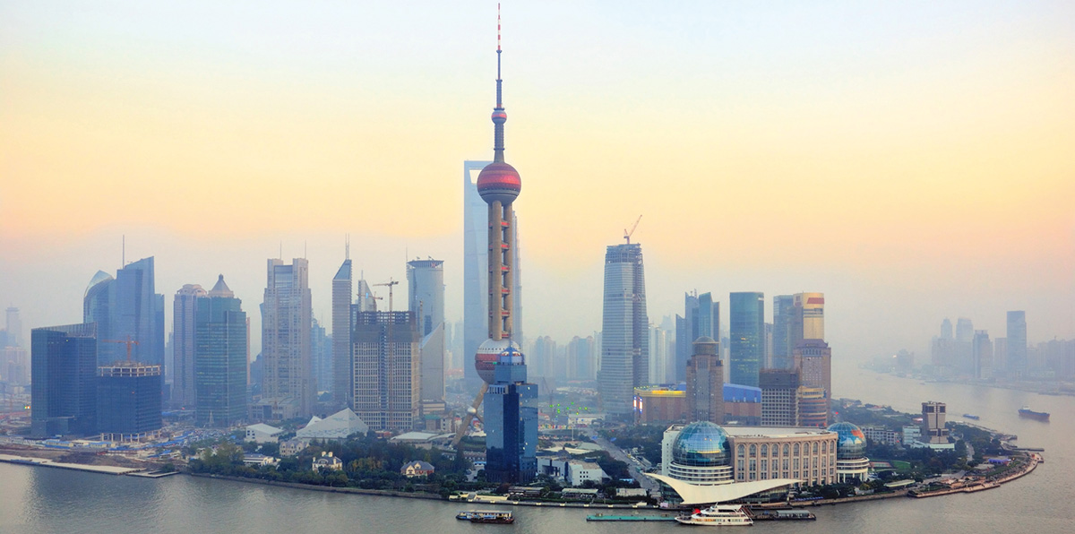 Skyline von Shanghai bei Sonnenuntergang mit dem ikonischen Oriental Pearl Tower und modernen Wolkenkratzern im Stadtteil Pudong