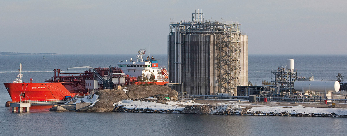 Industrielle LNG-Terminal-Anlage am Hafen von Nynäshamn an der schwedischen Ostseeküste mit großen Speichertanks und technischen Aufbauten vor grauem Himmel und Meereshintergrund